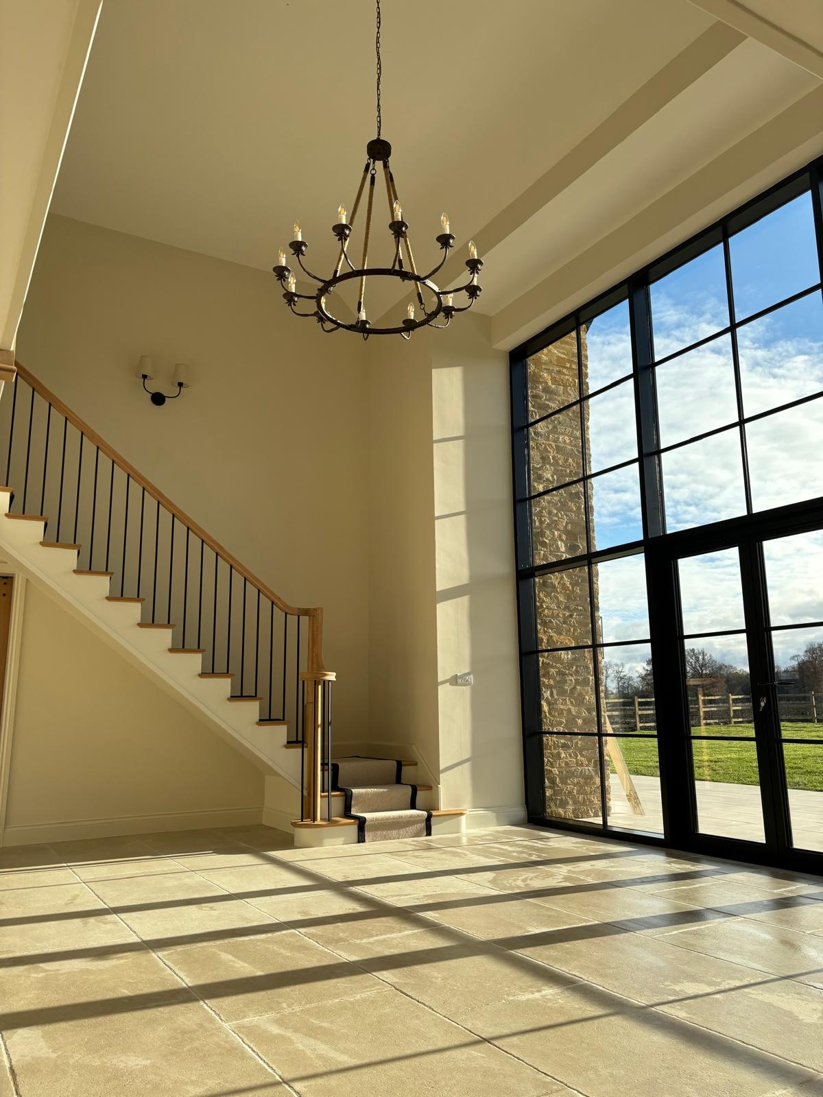 Stone floor entrance hall with chandelier and glazed doors