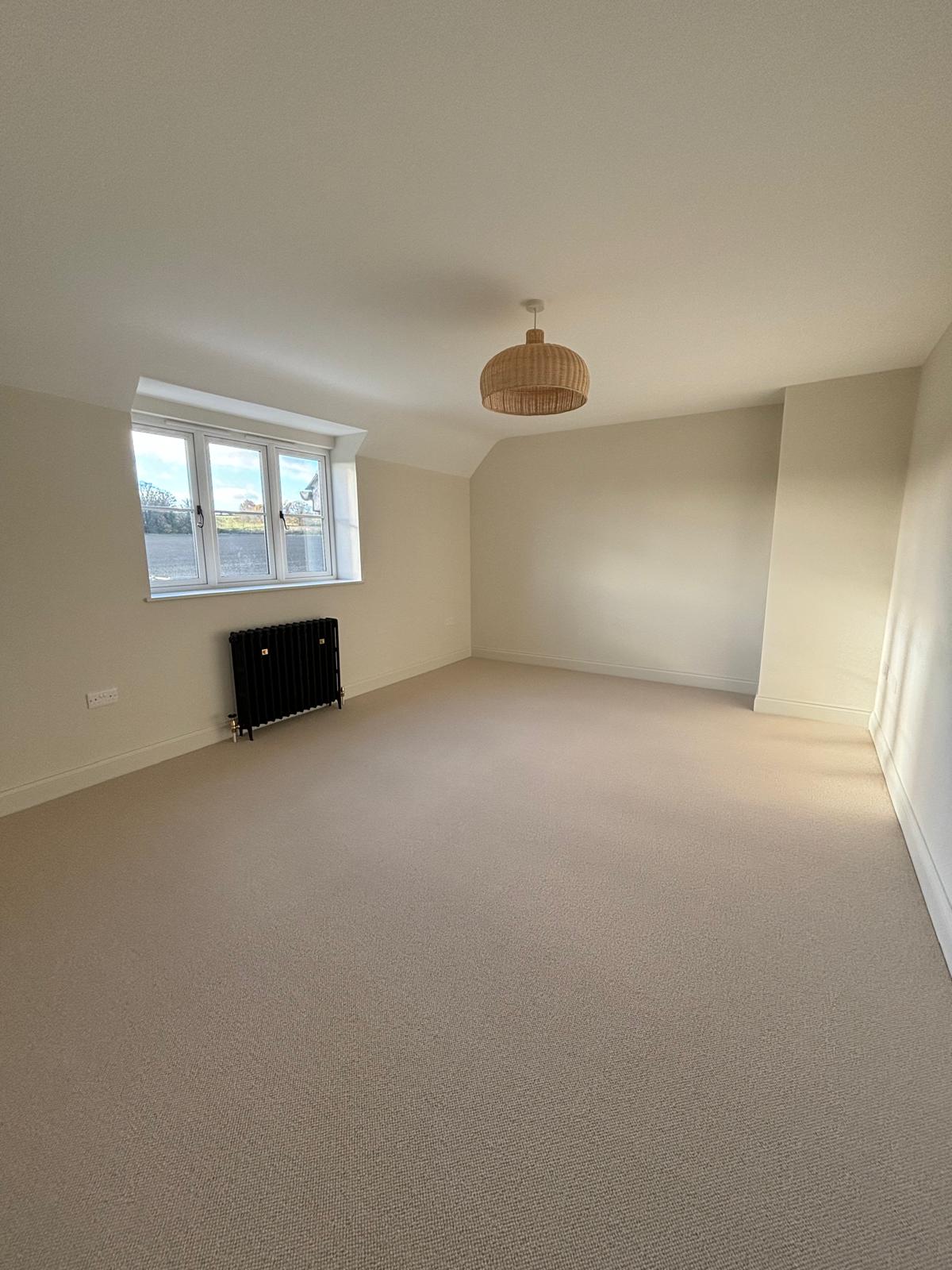 Spotless carpeted bedroom with window and black radiator cleaned